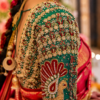 Close-up of handcrafted peacock sleeve Aari embroidery with kundan stones, pearls and Maggam work