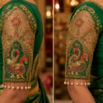 Close-up sleeve view of Emerald Green Peacock Aari Bridal Blouse showcasing peacock embroidery, floral vines, beads, pearls, and premium Aari embroidery.