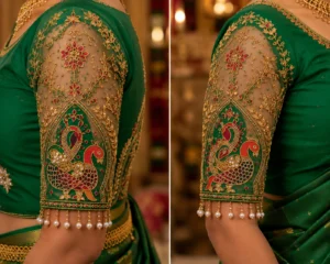 Close-up sleeve view of Emerald Green Peacock Aari Bridal Blouse showcasing peacock embroidery, floral vines, beads, pearls, and premium Aari embroidery.